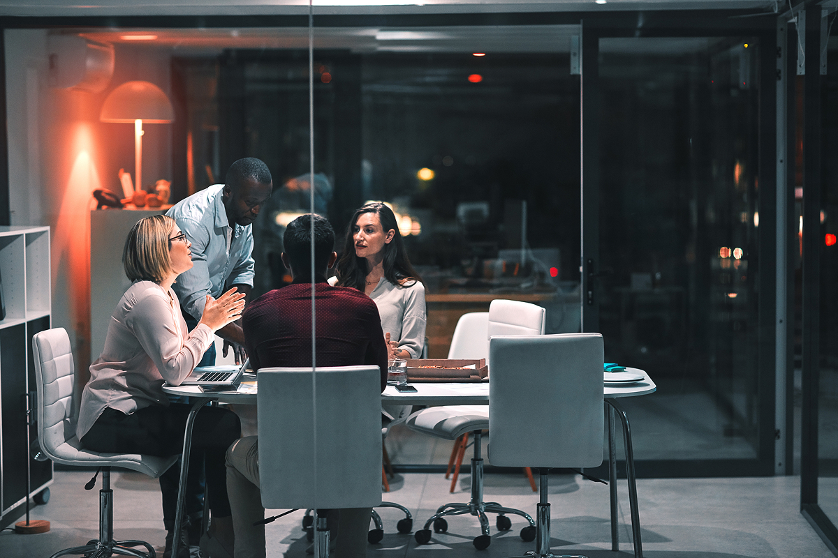 4 people working in a office sitting around a table discussing.